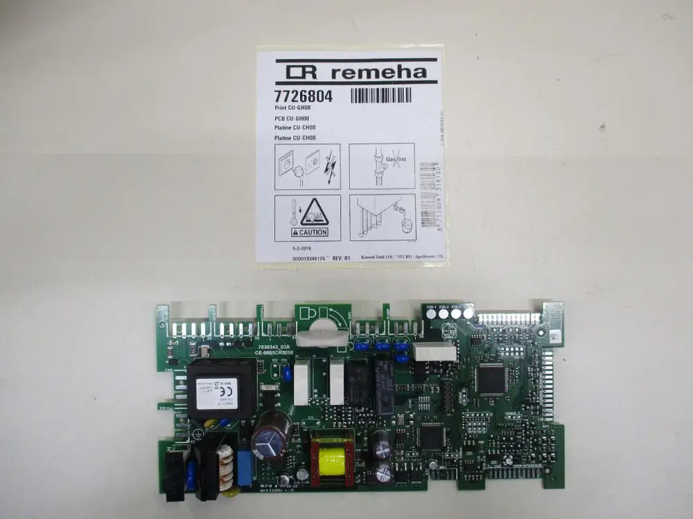 Elektroplatine von Remeha mit verschiedenen elektronischen Komponenten, darunter Widerstände, Kondensatoren und ein Transformator, auf einer grünen Leiterplatte abgebildet.